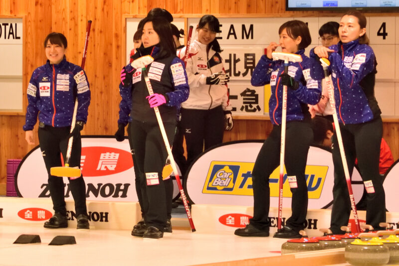 カーリングのブラシを持つ四人の女性