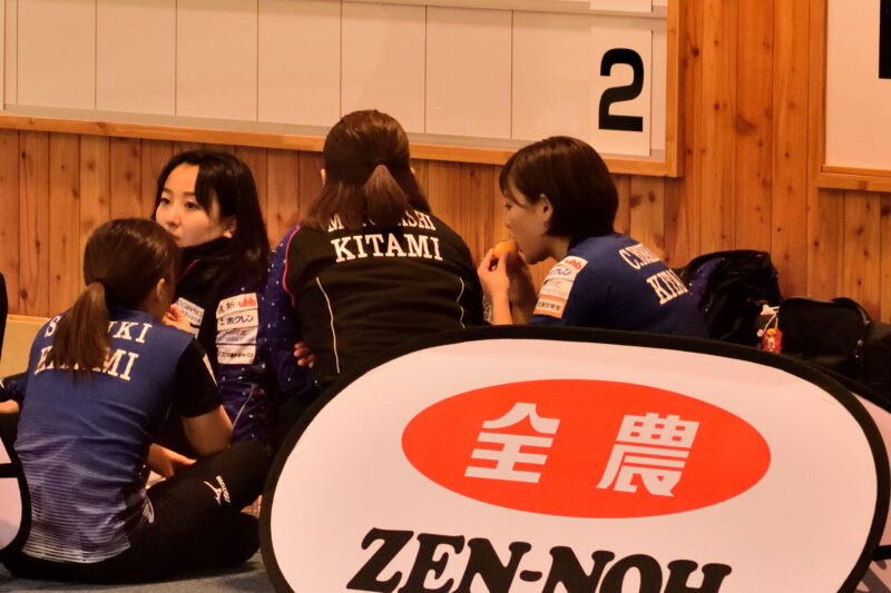 休憩をするカーリングのユニフォームを着た女性の集団