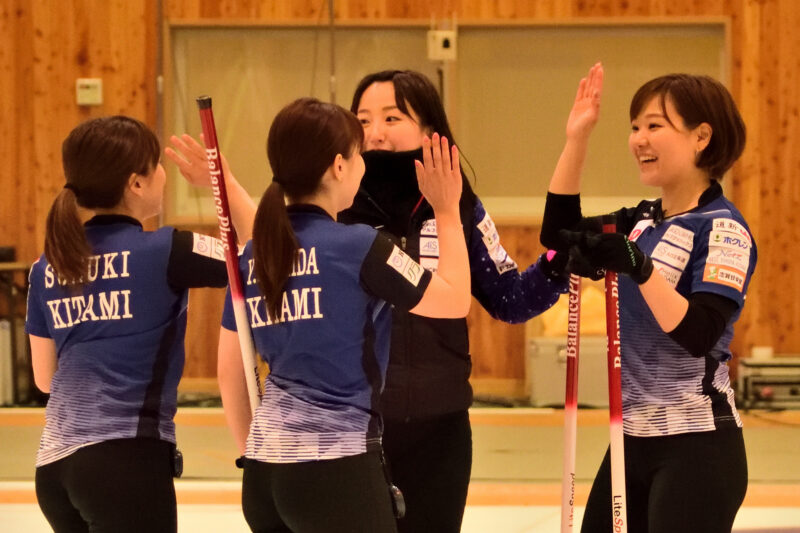 手を上げハイタッチをしようとする四人の女性