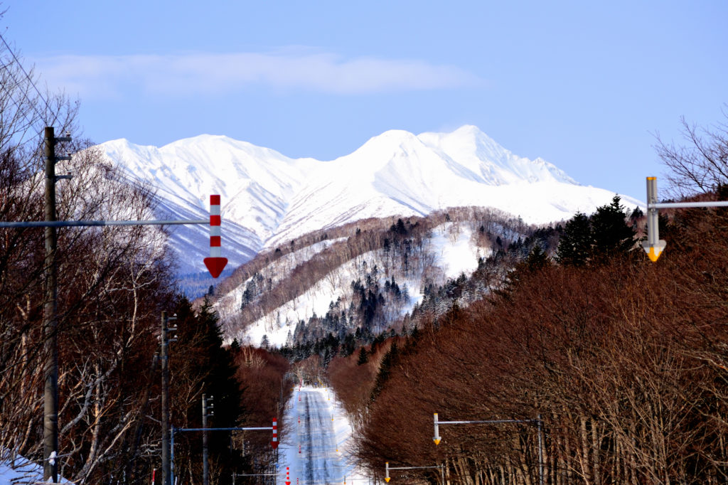 雪に覆われた山々に続く一本道