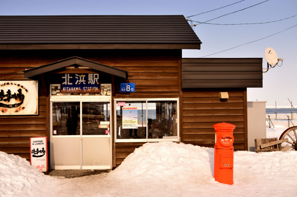 北の海沿いの駅舎と赤いポスト