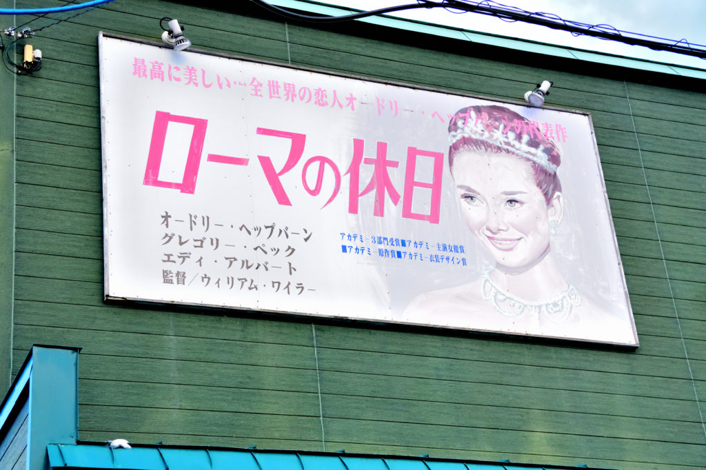 緑の壁に貼られたローマの休日の看板